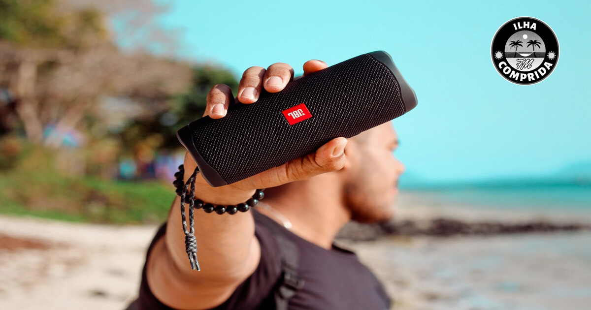 Pessoa ouvindo web rádio na praia com celular e fones de ouvido